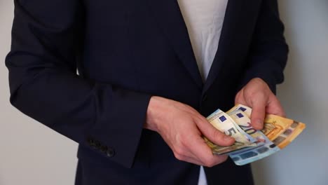 man in a suit counting euro banknotes in his hands