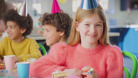 portrait of girl with birthday cake and party blower at party with parents and friends at home