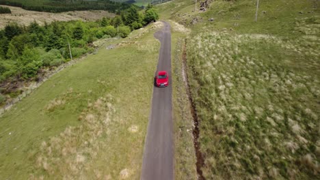 Aerial-footage-red-car-driving-along-single-track-road-in-the-countryside