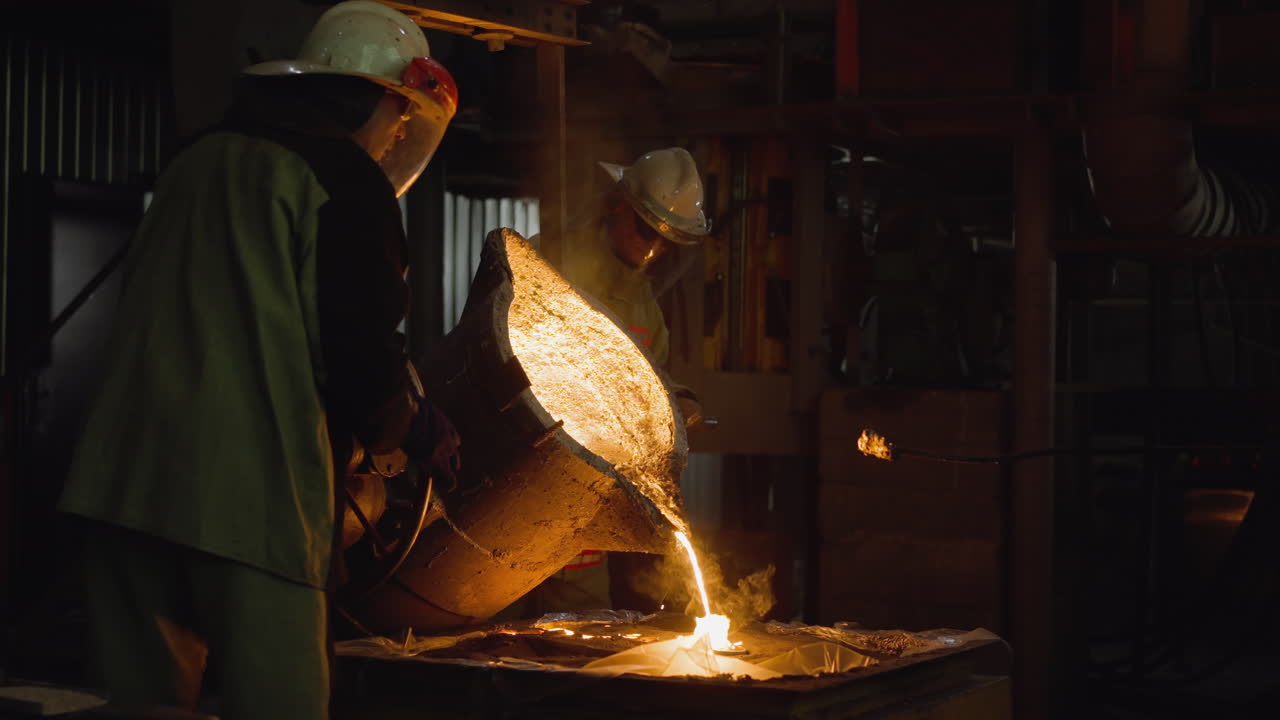 команда литейных рабочих наливает светящееся расплавленное железо из ложки в формы