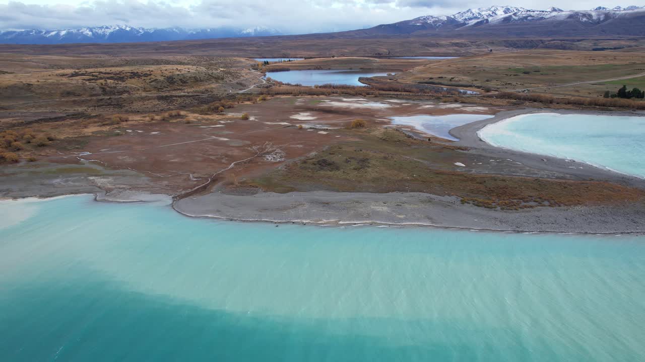 Rugged Peninsula Surrounded By Lake Tekapo's Turquoise Waters In South Island Of New Zealand. aerial pullback shot