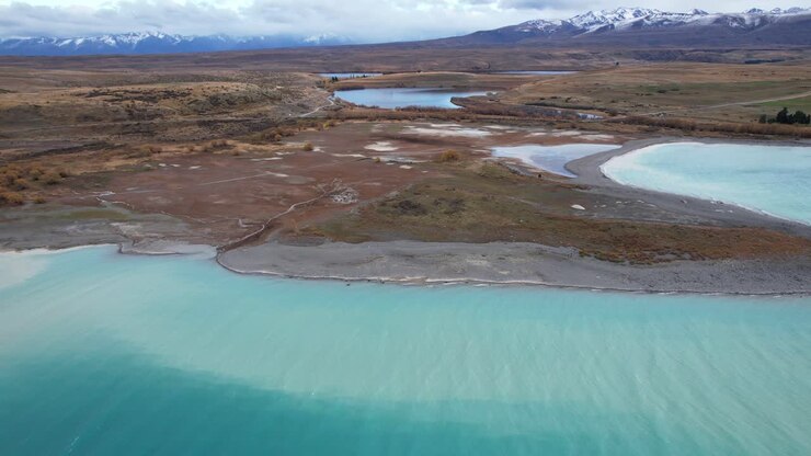Penisola aspra circondata dalle acque turchesi del Lago Tekapo nell'Isola del Sud della Nuova Zelanda. Ripresa aerea con allontanamento