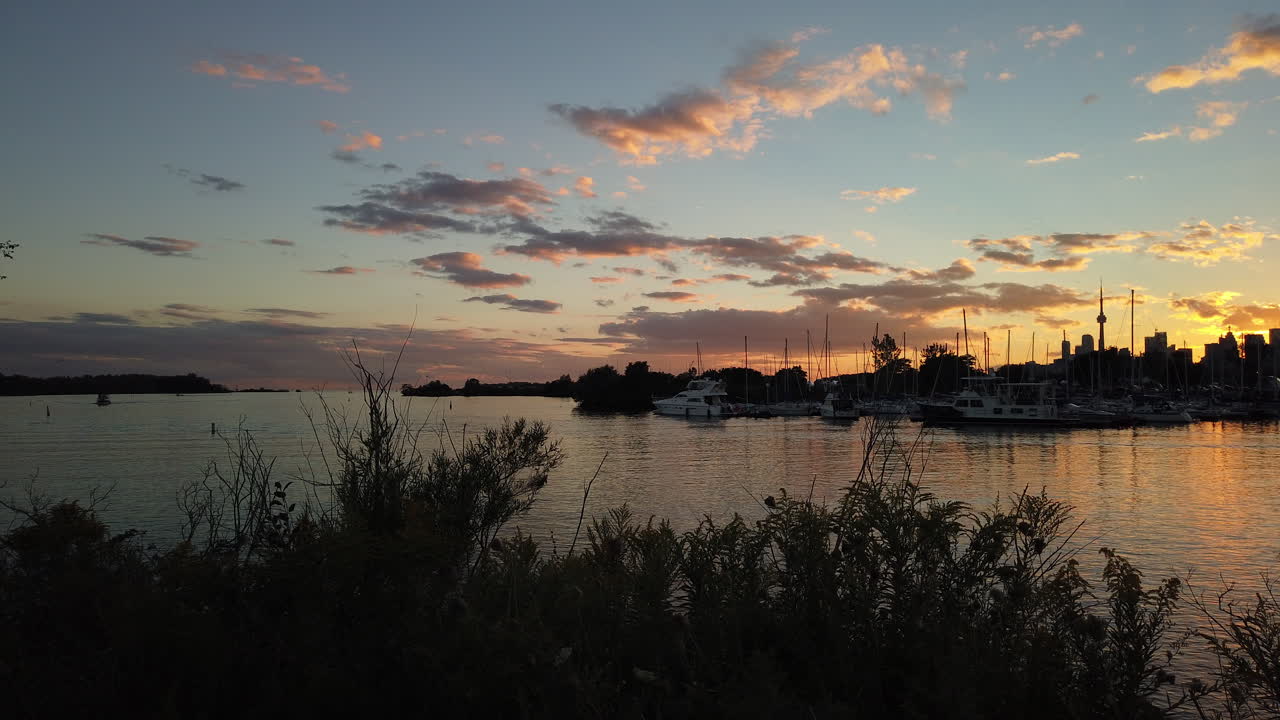 Weitwinkel-Zeitrafferaufnahme von Segelbooten, die bei Sonnenuntergang in einen Yachthafen zurückkehren