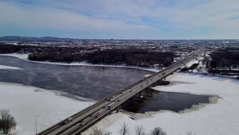 Autos-Fahren-An-Kalten-Wintertagen-Auf-Der-Brücke-über-Den-Zugefrorenen-Und-Schneebedeckten-Fluss