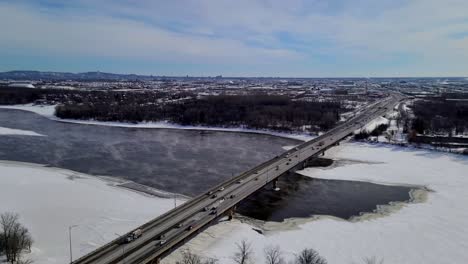 coches circulando por un puente sobre un río helado y nevado en un frío día de invierno