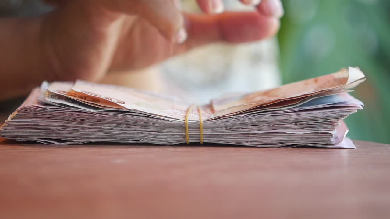 Close up of a hand holding a stack of Thai baht