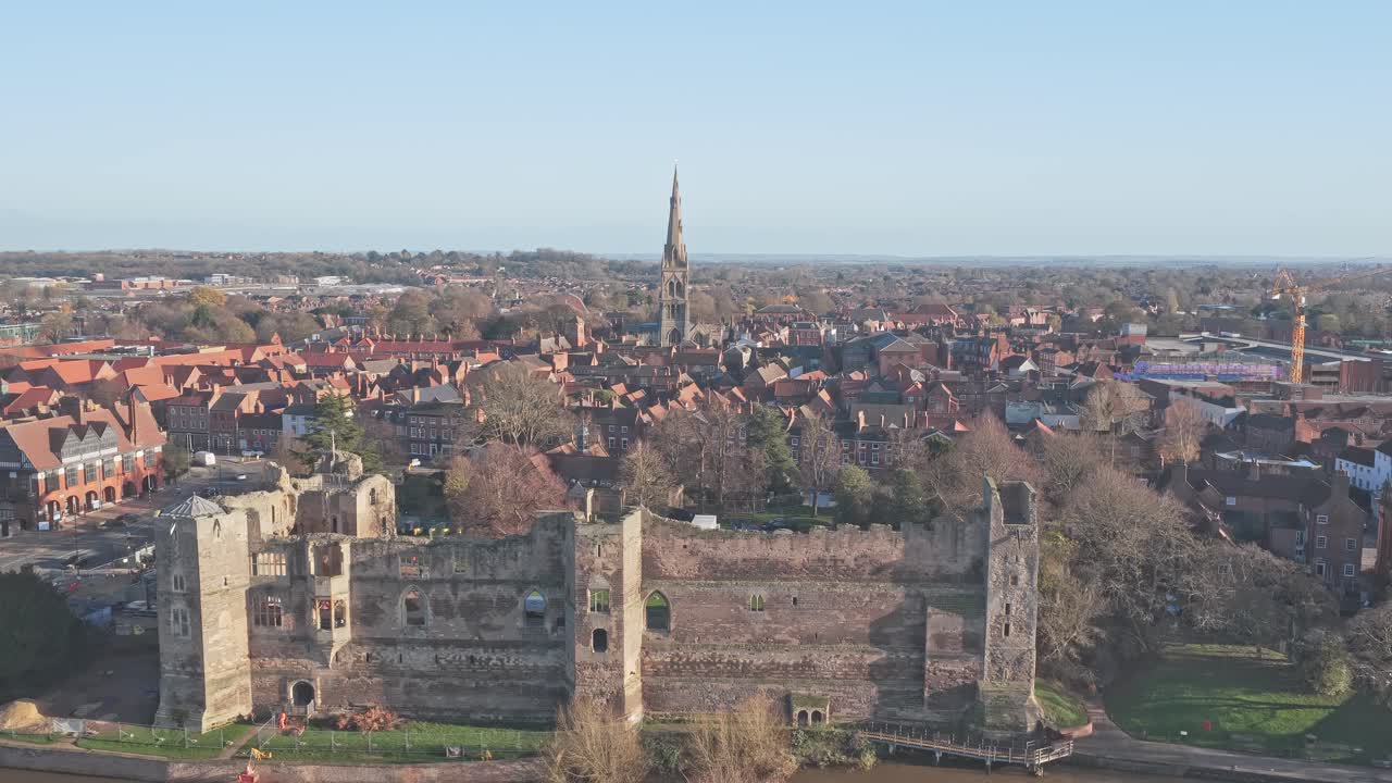 Newark Castle ruins beside the River Trent with the town and All Saints Church spire in the background, a riverside medieval landmark reflecting Englands historic architecture and heritage