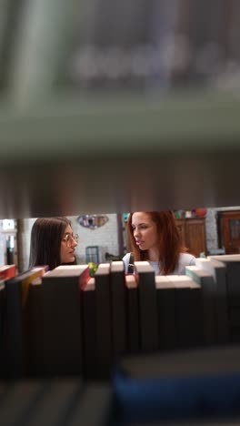 two young women talking in a library