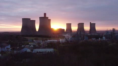 Fiddlers-Ferry-disused-coal-fired-power-station-as-sunrise-emerges-from-behind-landmark,-Aerial-view-rising