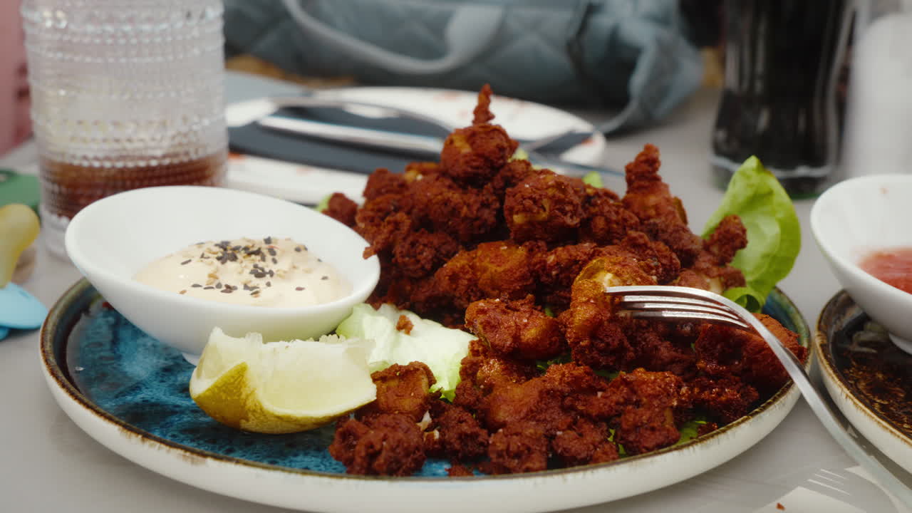 Crispy baby squids served with lime and dip on a ceramic plate. Perfect for food documentaries or cooking shows.