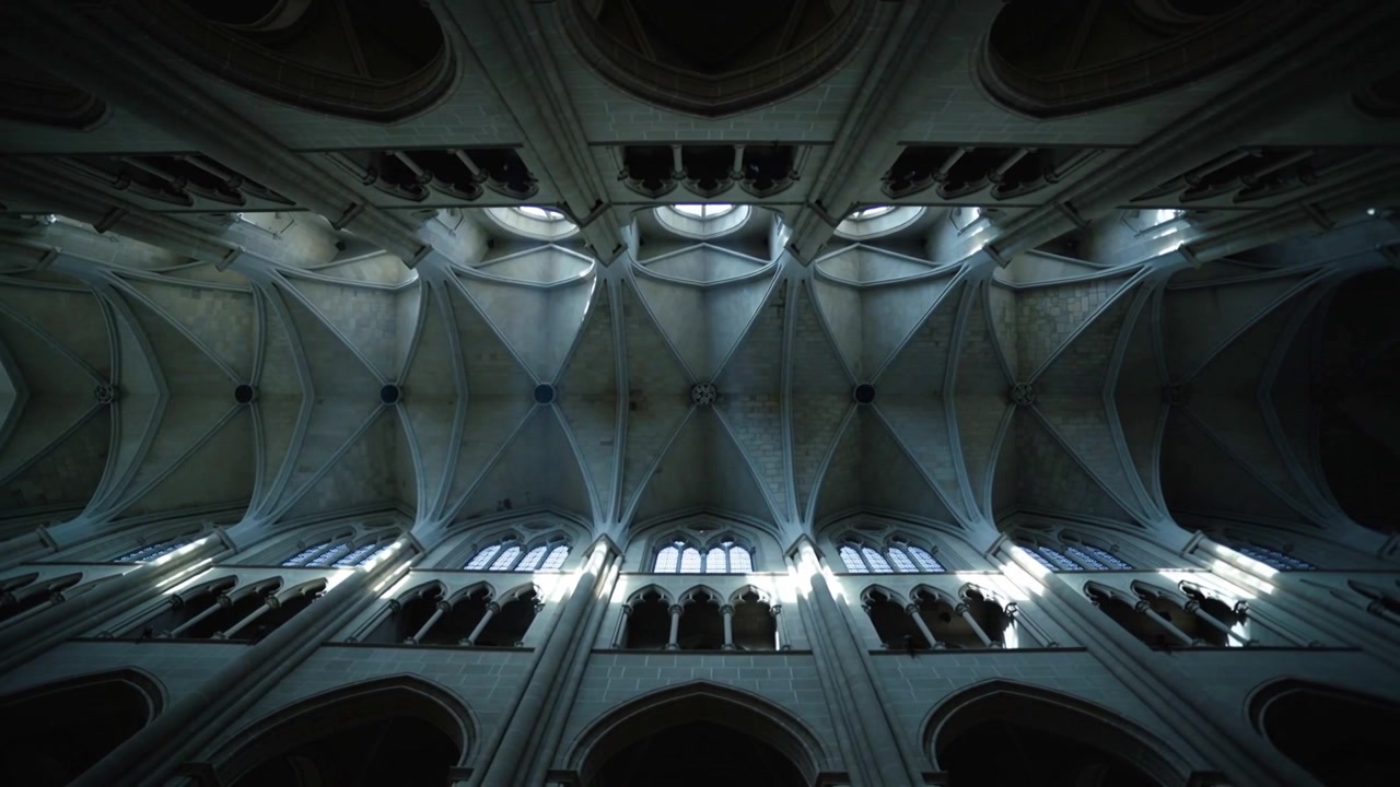 Filming camera capturing nave vaults showing light shift and clerestory windows, emphasizing ribs