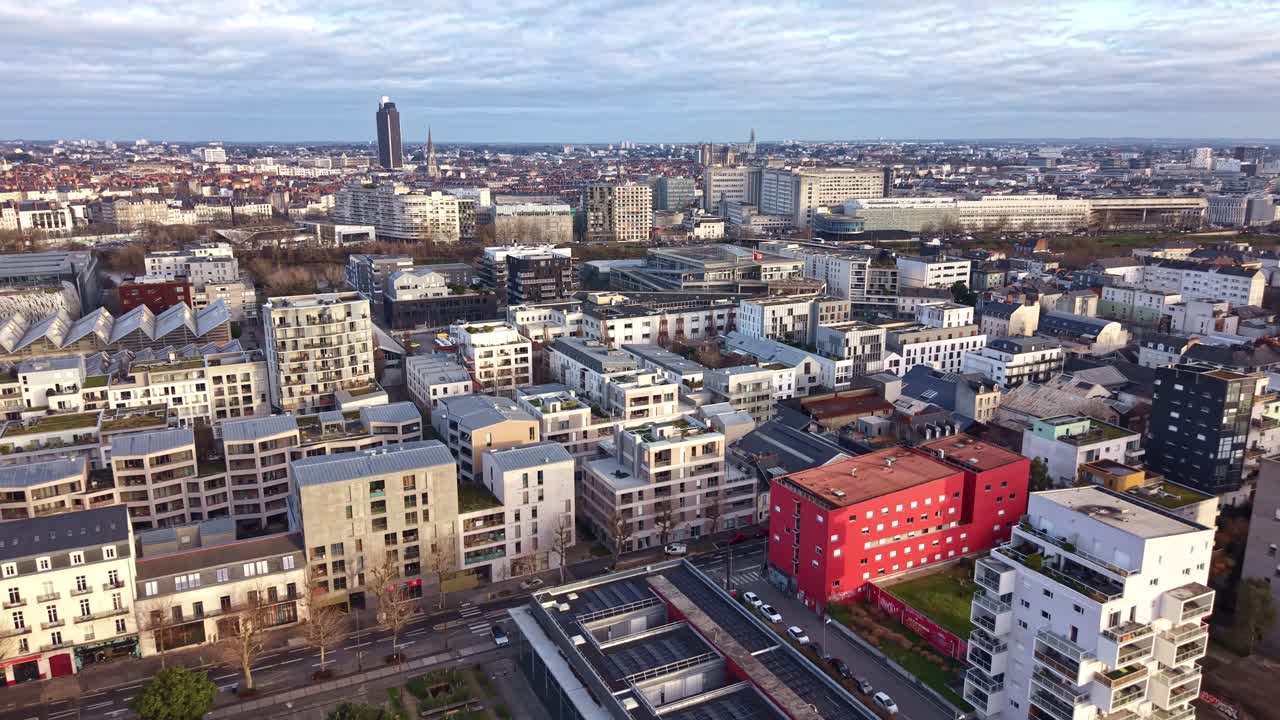 Droneflyvning over Nantes' bybillede med bygninger og Tour de Bretagne under en skyet himmel