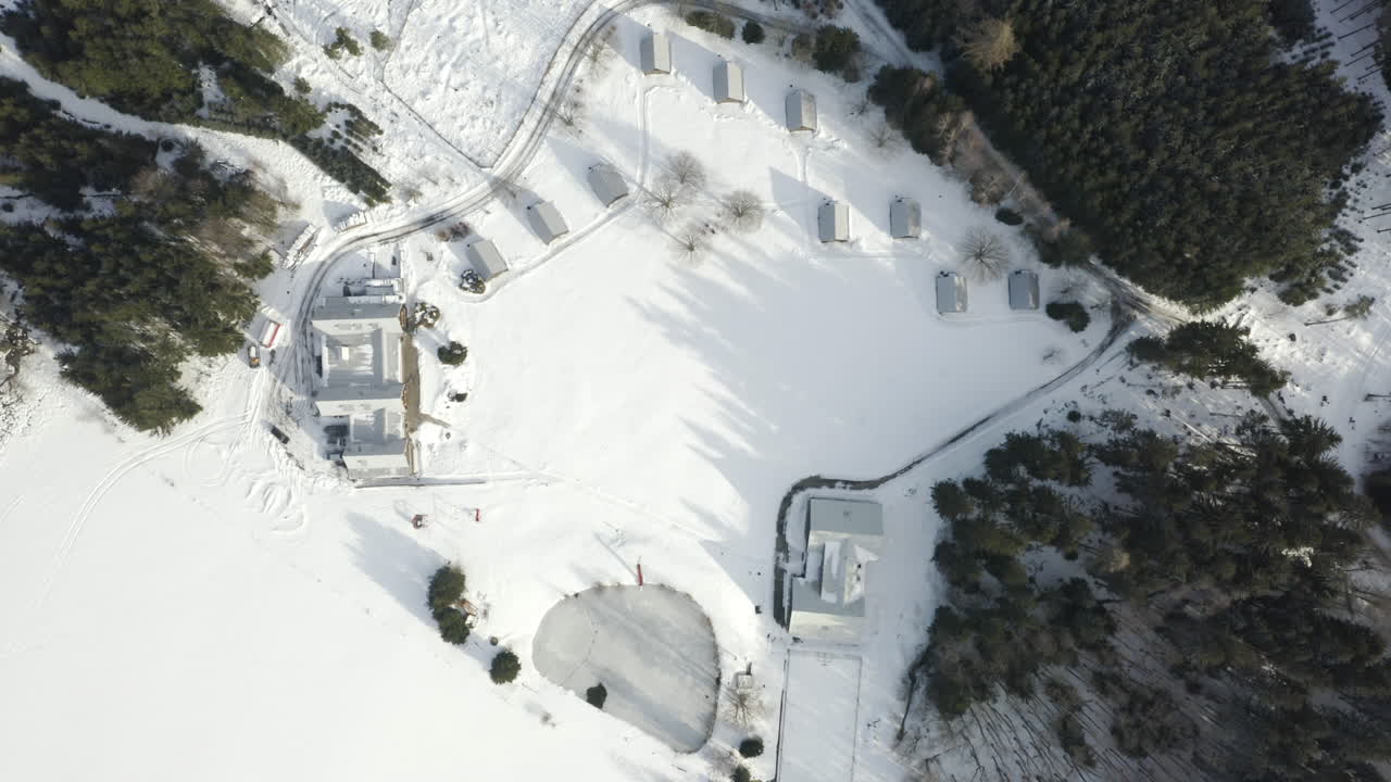 toma aérea del campamento de esquí alpino en un paisaje cubierto de nieve con cabañas y árboles forestales