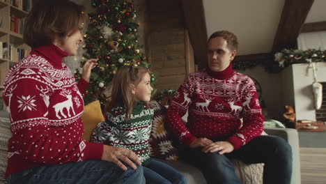 linda niña sentada con sus padres en el sofá y dando un regalo de navidad a su amado padre