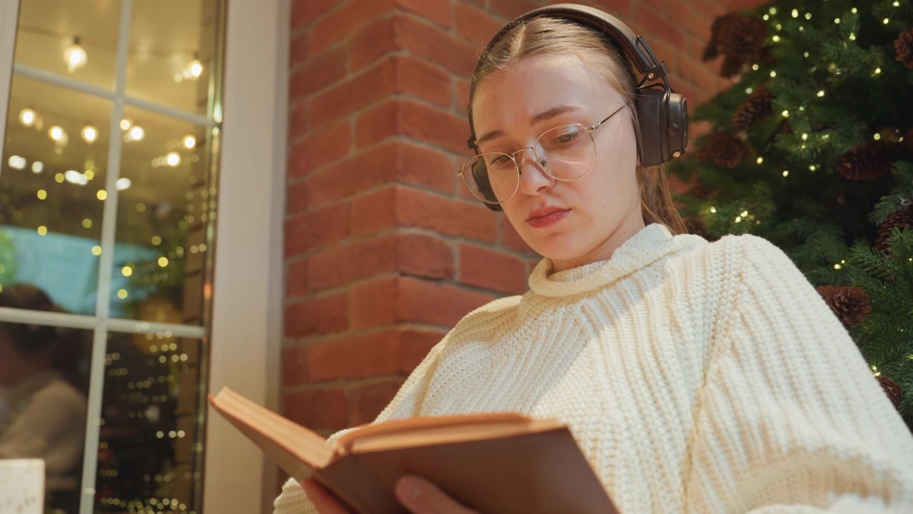 Jeune femme lisant un livre avec un casque dans un cadre de Noël douillet