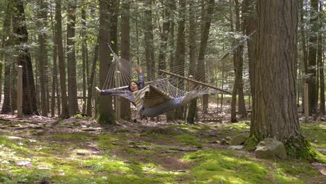 jovem fêmea adulta esticando e balançando em uma hamaca na floresta desfrutando de um estilo de vida relaxado