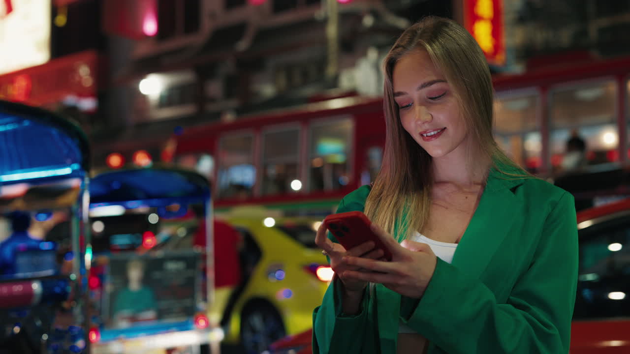 Woman using phone in a vibrant night city street
