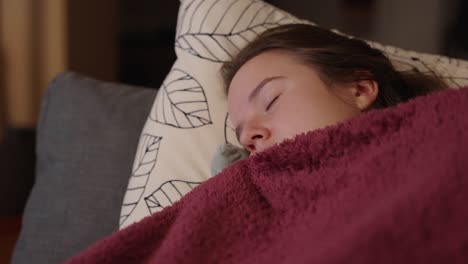 Closeup-of-cute-woman-sleeping-on-sofa-with-comfy-blanket-after-long-day-of-work