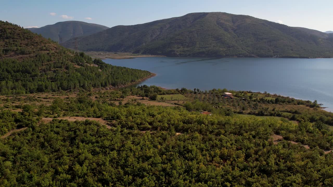 산악 호수 기슭에 있는 마을, 알바니아의 오래된 집과 과수원이 있는 시골 풍경