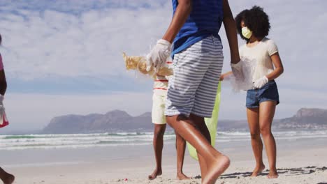 Padres-Afroamericanos-Con-Dos-Niños-Usando-Máscaras-Recogiendo-Basura-De-La-Playa