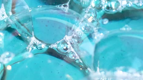 detailed view of transparent bubbles and foam interacting on a vibrant blue water surface.
