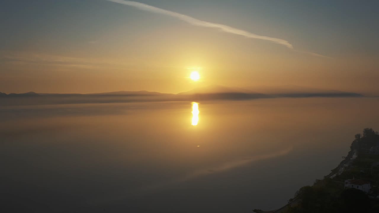 Drone flying above a  golden misty sea shore on golden hour sunset, aerial over misty water surface in Lesvos, Greece.