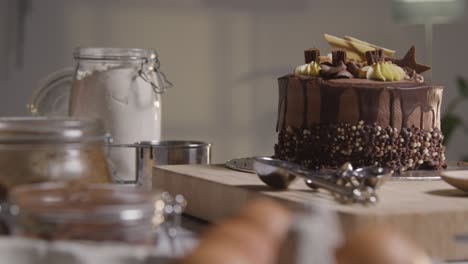 Close-Up-Of-Kitchen-With-Freshly-Baked-And-Decorated-Chocolate-Celebration-Cake-On-Work-Surface