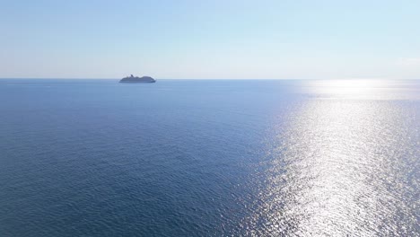 cruise ship on horizon drives across open blue water as sunlight shimmers on water