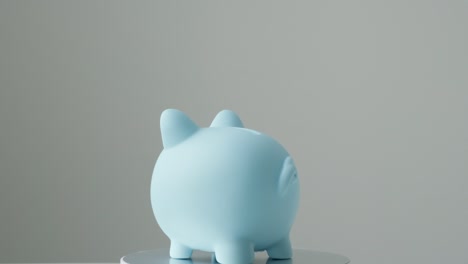 spinning blue piggy bank on gray background. pension, vacations, currency, savings, finance accounting