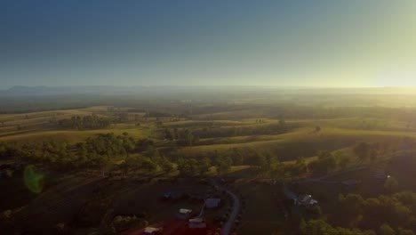 Aerial-drone-pulling-back-rolling-hills-at-sunrise,-in-the-Hunter-Valley-wine-region,-Australia
