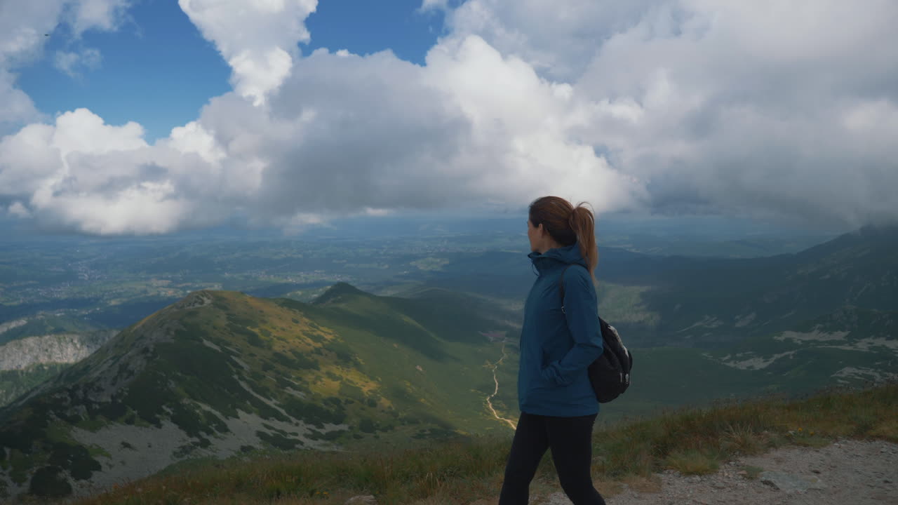 Female hiker admiring the beautiful view of green mountains on a cloudy day. Poland