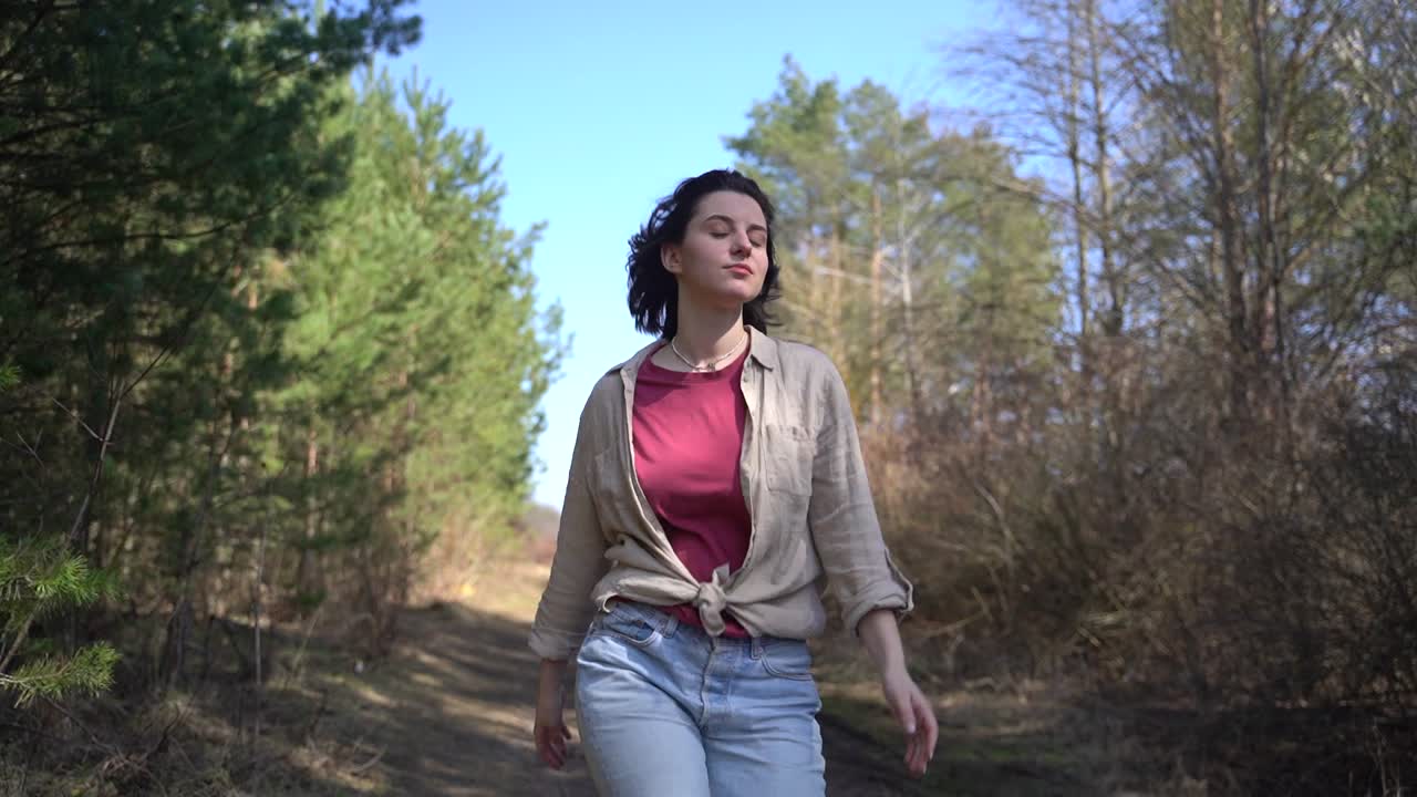 A young beautiful brunette girl runs through a pine forest.