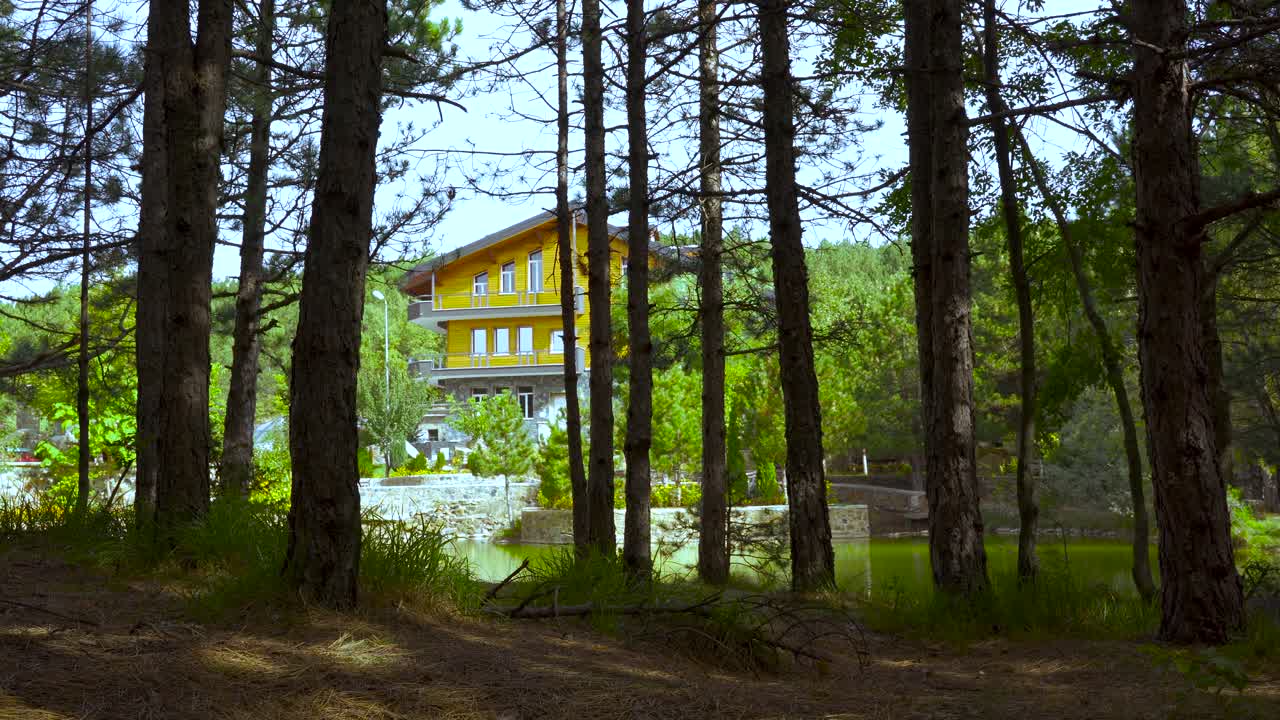hotel en las montañas cerca de un lago rodeado de bosques de pinos, destino de vacaciones paradisíaco en los alpes