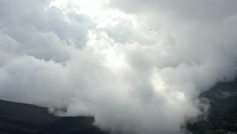 green forest valley covered in clouds fog, low visibility aerial sky drone