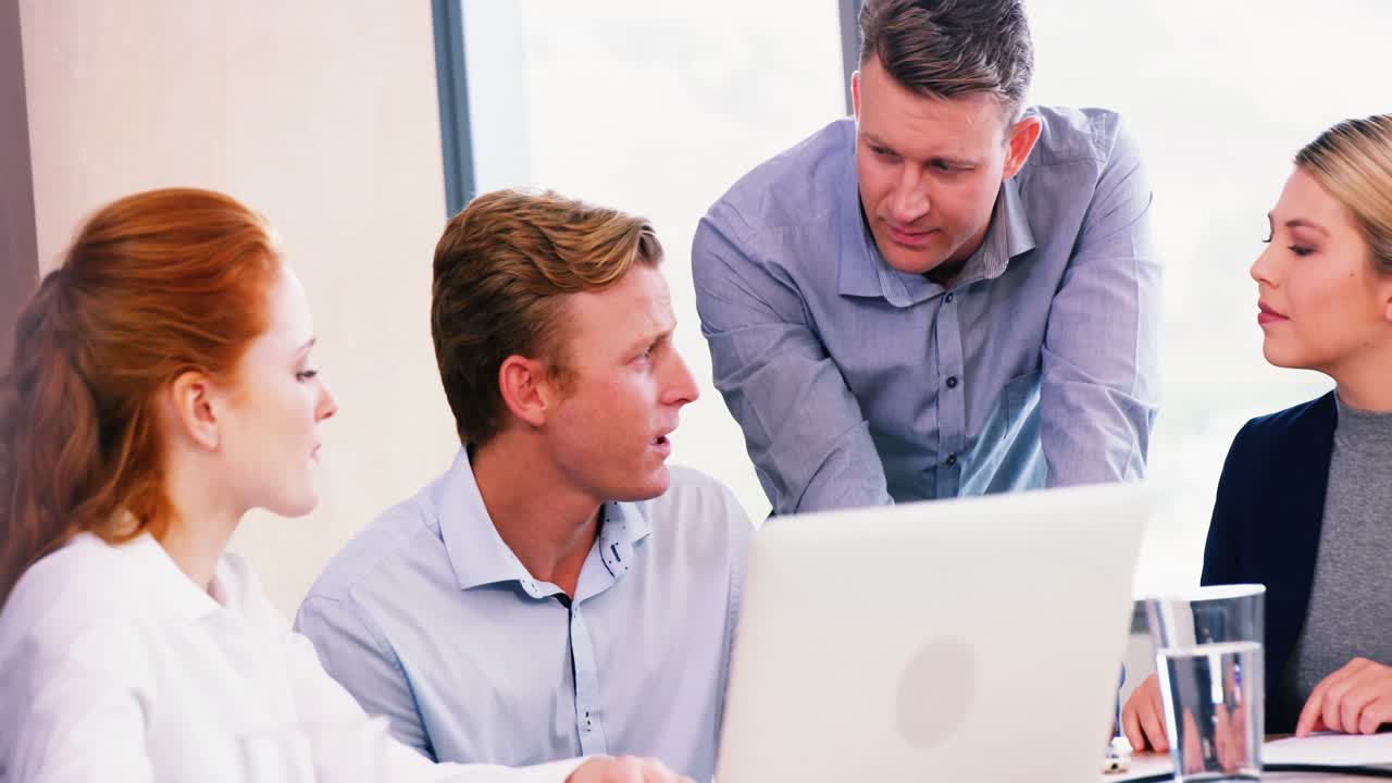 Executives discussing over laptop