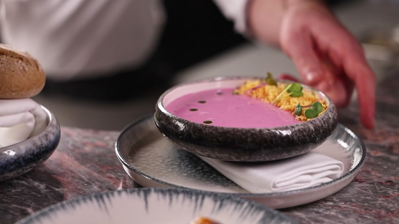 Chef che Presenta una Ciotola Gourmet di Zuppa Cremosa di Barbabietola