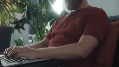 man sitting on sofa and working on laptop