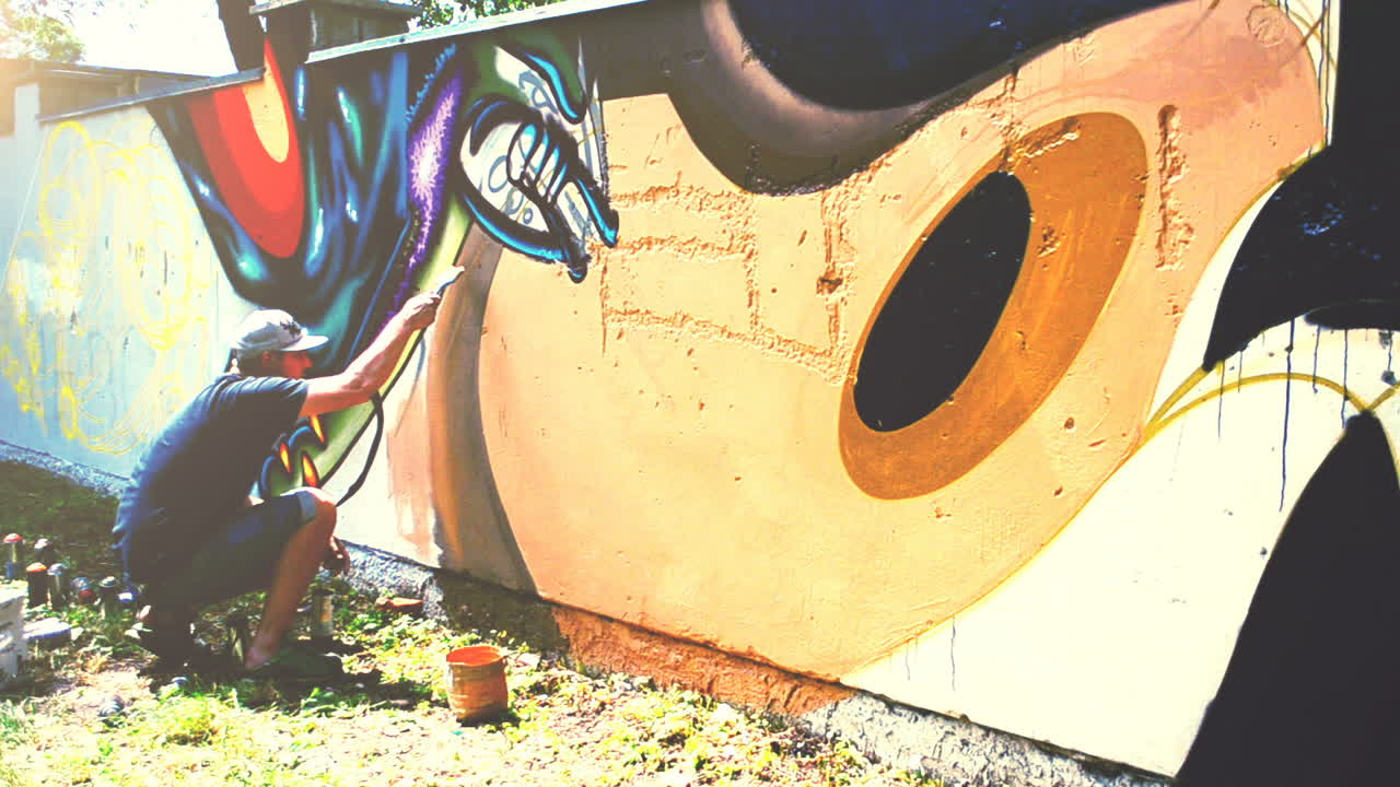 L'artista realizza graffiti su una recinzione. Disegno astratto