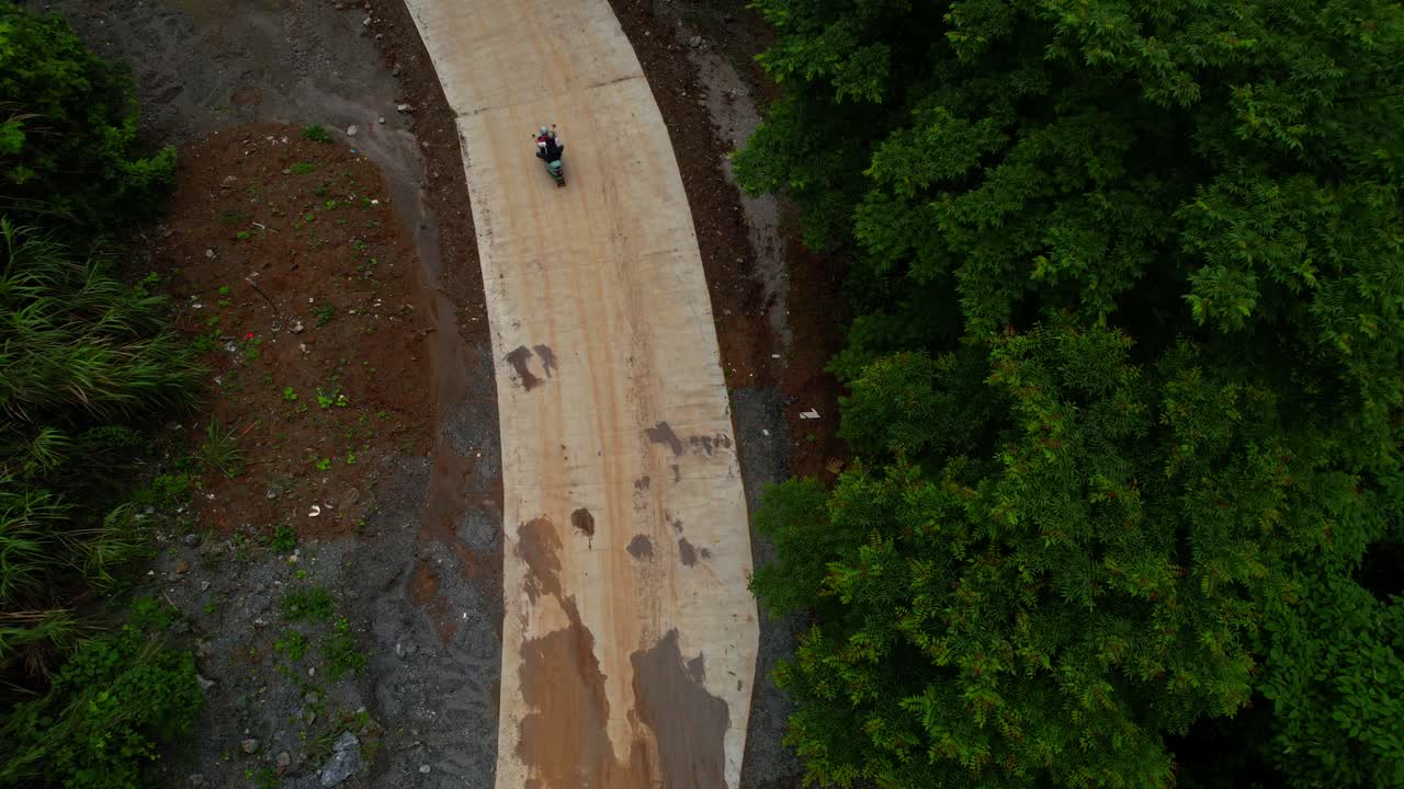 una pareja en un scooter eléctrico viaja por un camino aislado en la exuberante yangshuo, guilin