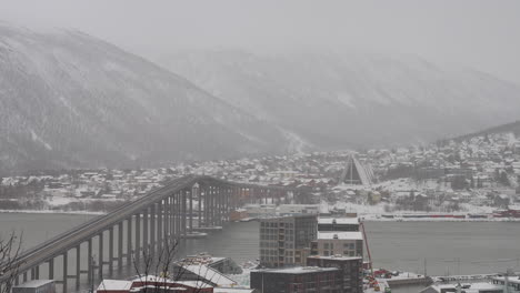 Time-lapse-of-traffic-over-Tromso-bridge-toward-Arctic-Cathedral,-snowy-winter