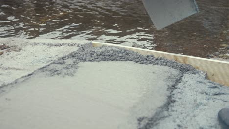 shoveling some mixed cement onto edge slow motion