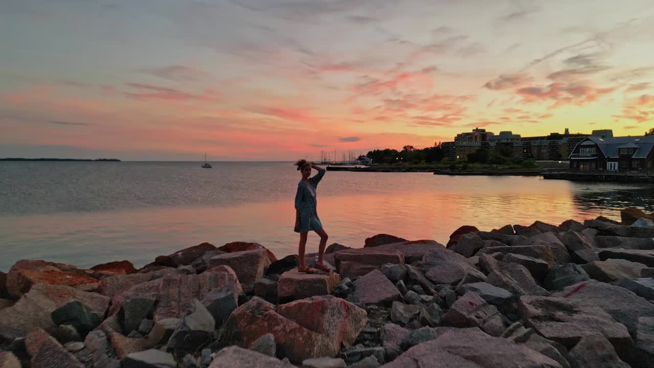 배경 공중 드론 샷에서 일몰과 함께 카메라에 미소 짓는 젊은 여성