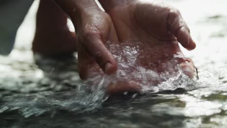 manos sacando agua en un río en una cascada en la isla de vancouver