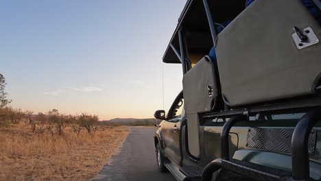POV of side of safari truck driving on savanna road at dawn golden hour