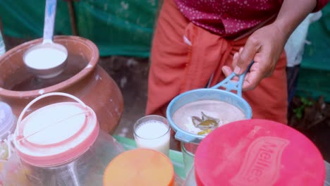 Witness-a-captivating-close-up-of-a-man-in-traditional-attire-pouring-lazzi,-a-delightful-Indian-beverage,-from-a-clay-pot-to-a-glass-using-a-skillful-straining-technique