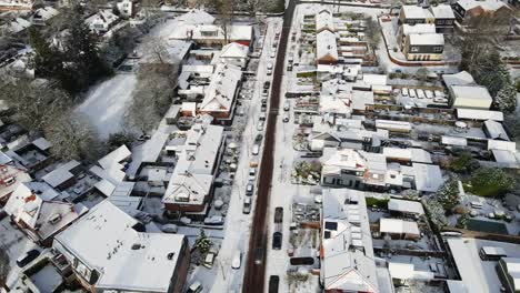 aerial de un coche conduciendo por un camino limpio en una hermosa ciudad cubierta de nieve