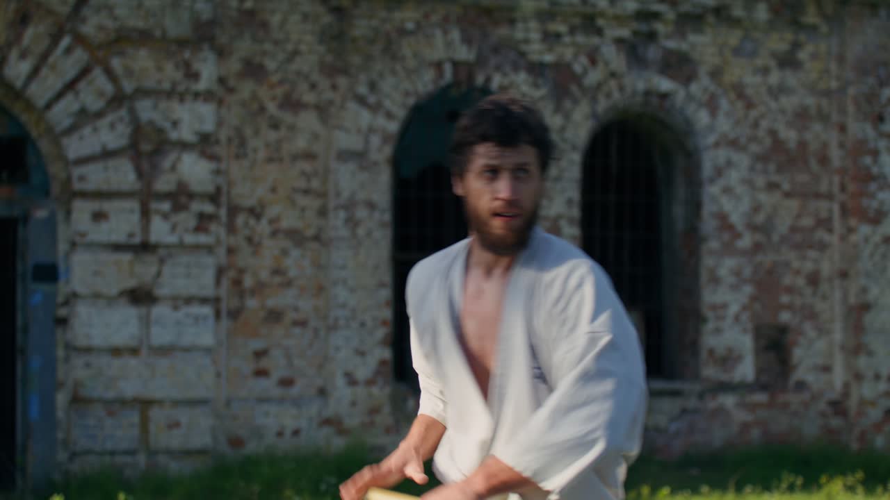 Mann som trener karate med nunchucks utendørs