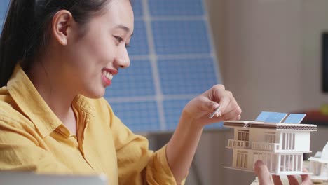 woman designing a sustainable home model with solar panels