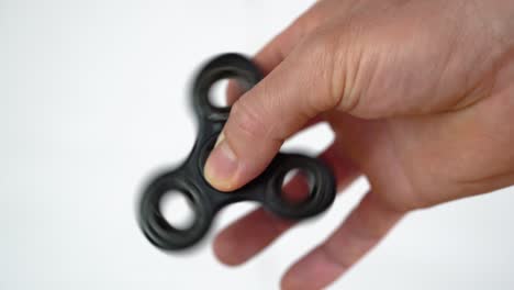 popular fidget spinner toy rotating between fingers of white man