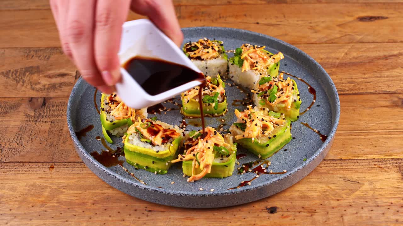 closeup of a plate of avocado sushi that is smothered in Worcestershire sauce